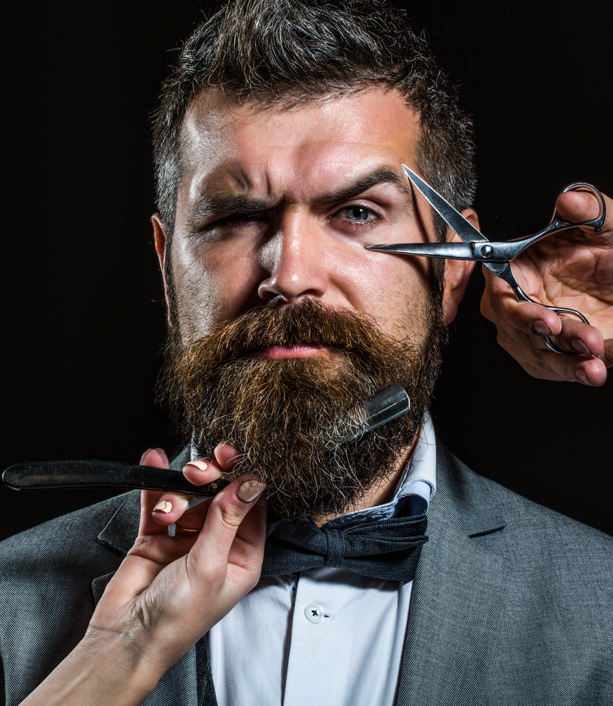 Un homme qui montre le ciseau et le rasoir pour montrer la belle experience chez le barbier
