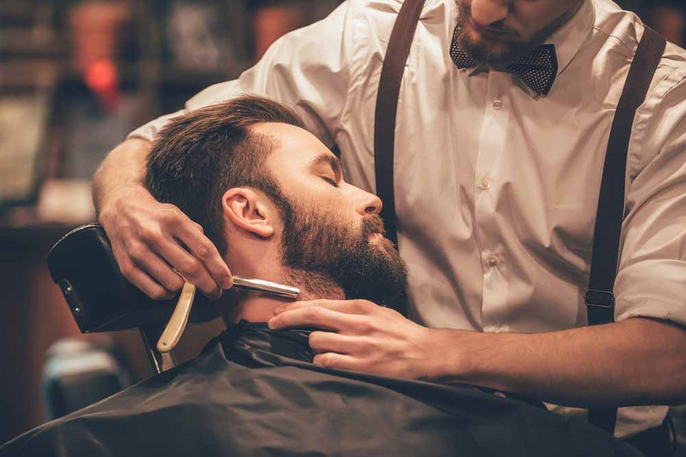 Un barbier qui fait le rasage à lame
